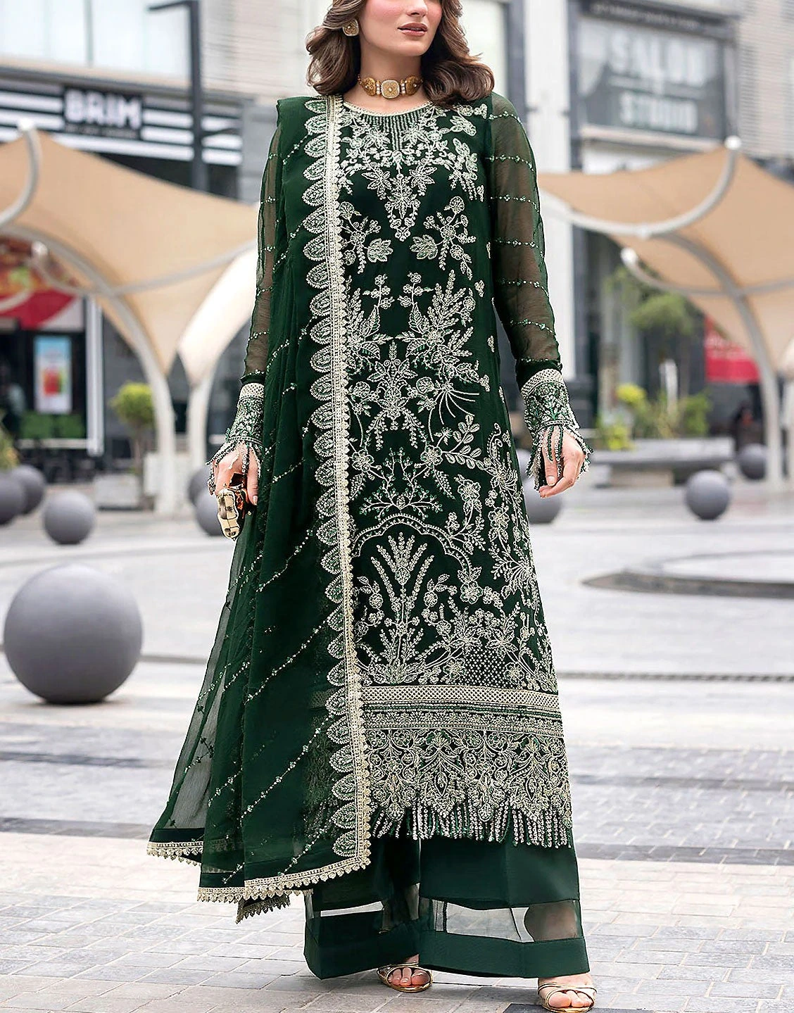 Deep-green embroidered kameez with a scalloped sheer dupatta, worn outdoors