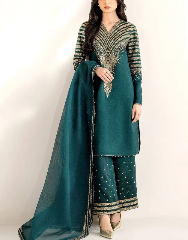 Dusty-blue silk outfit with a multicoloured embroidered border, modelled against a warm studio backdrop